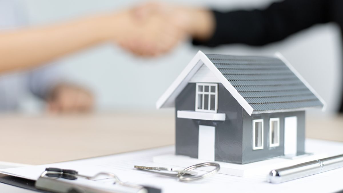 figure of a house with 2 people shaking hands in the background